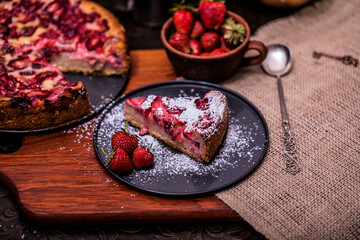 Pie with rhubarb and organic strawberries on a dark wooden background with fresh strawberries. Selective focus and vintage image.