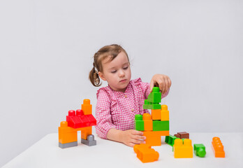 Little girl learn to build from a constructor on a white background.