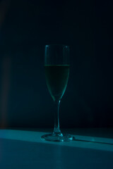 Transparent, beautiful glass with champagne stands on a white table on a blue background
