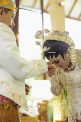 Beautiful indonesian bride kissing groom hands, after wedding ceremony for symbol loyalty.