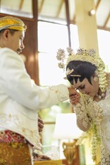 Beautiful indonesian bride kissing groom hands, after wedding ceremony for symbol loyalty.