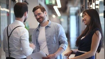 Happy diverse colleagues greeting talking standing in office hall, smiling multiethnic staff professional people giving high five chatting laughing enjoy friendly conversation meeting in work space