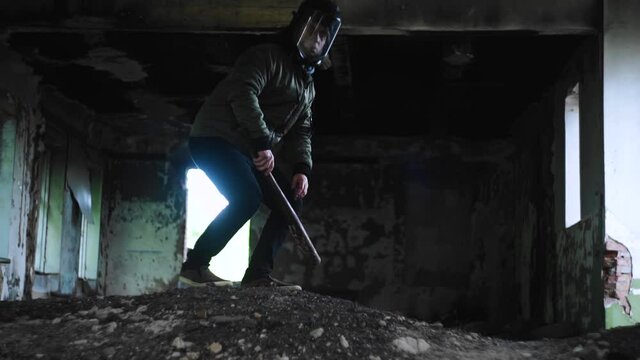 A guy in a hard hat inspects an old building. He's holding a baseball bat. Apocalyptic atmosphere