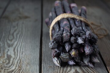 Fresh bunch of purple asparagus on a wooden background.