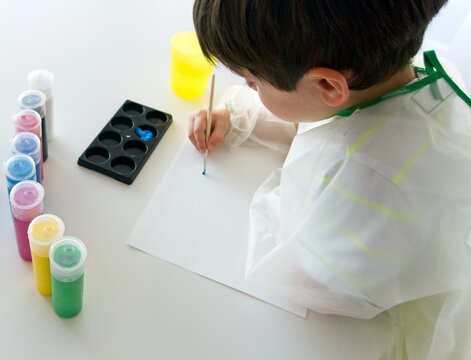 Boy painting with paint a white paper