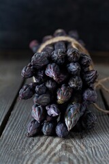 Fresh bunch of purple asparagus on a wooden background.