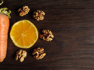 Carrots, orange and walnuts on a dark wooden background, top view. Ingredients for Carrot Cake