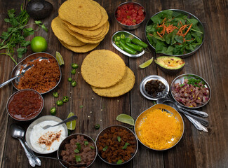 Vegetarian corn tostada with a variety of side toppings on wooden table
