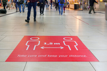 Selected focus low angle view at " Keep your distance", on red rectangular caution sign on the floor inside Main Train Station in Germany during Social Distancing by epidemic of COVID-19.