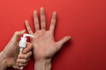 Gel hands on medical red background. Washing hands with antibacterial sanitizer gel in lab gloves. Clear sanitizer in pump bottle. Corona Virus pandemic protection by washing hands frequently