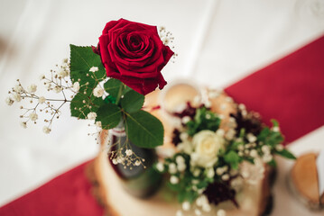 Red rose close up. Flower in vase on festive table. Red and white background. Copy space.