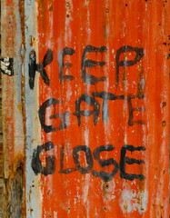 KEEP GATE CLOSE signage written on red painted rippled corrugated metal.