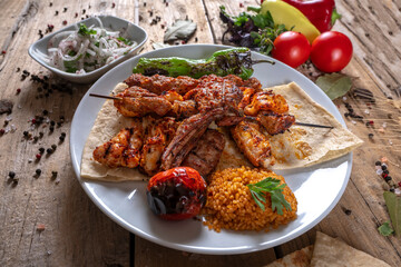 Served with traditional lamb chops, kebabs, meatballs, mixed grilled tomatoes, peppers and rice cooked on the grill. service with white plate. Grilled lamb with vegetables on the grill top view. 