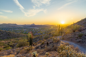 A desert trail on a mountain leading to a sunset over a valley in Phoenix Arizona