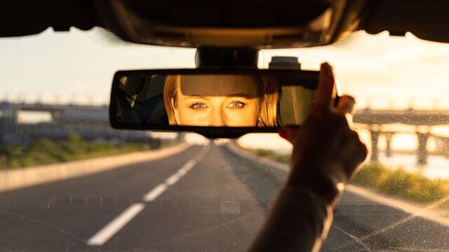 Cheerful joyful woman adjusting mirror while sitting in her car, looking in reflection at camera. Sunset time.
Emotions from driving car - Powered by Adobe