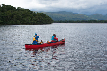 Two people and a dog canoeing in Loch Lomond, Scotland.