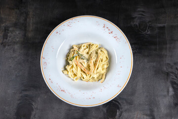 Chicken Mushroom Alfredo Fettucini Pasta : Creamy Cheese Sauce of pasta serve in white plate with background black wood table