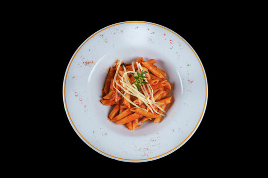 Penne pasta with chili sauce arrabiata and slice cheese. Top view isolated black background