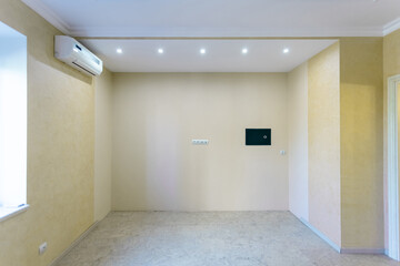 small unfurnished room with yellow walls, wall safe and air conditioning