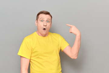 Portrait of funny amazed man pointing with index finger at himself