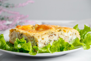 Fish pie on a plate. A piece of cake with mackerel and greens on a white background.
