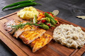 Grilled chicken fillet. Fresh grilled chicken steak on rustic black wooden background. Chicken steak kebab and eggplant paste with mashed potatoes delicious chicken dish.