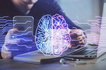 Double exposure of man's hand holding and using a digital device and brain hologram drawing. Data...