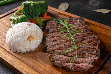 Grilled lamb chops with rosemary stalk. Fresh grilled steaks on rustic wooden background. Steak kebab and rice pilaf, close up
