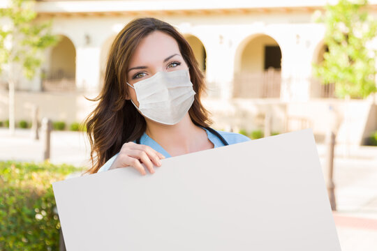 Female Doctor Or Nurse Wearing Protective Face Mask Holding Blank Sign