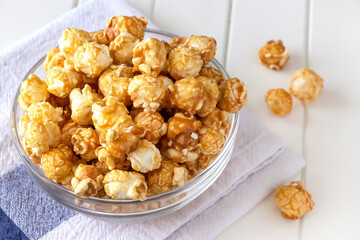 Sweet caramel popcorn in glass bowl. Close up. Light background.