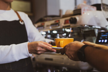Coffee Business Concept.Asian woman wear blue apron holding hot coffee cup Submit to the customer