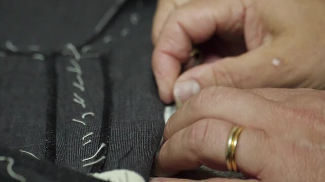 tailor sewing pants with needle and thread slow motion