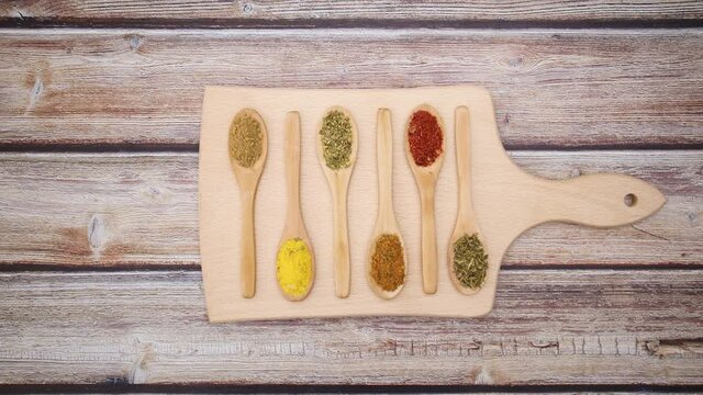 Cutting board and wooden spoons with spices appear on wooden table - Stop motion 