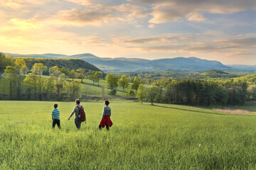 Family hiking in a beautiful scenery at sunset - obrazy, fototapety, plakaty