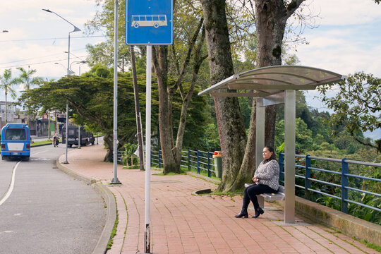 Woman sitting at the whereabouts waiting for the bus