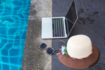 Fototapeta na wymiar hat and laptop on the pool