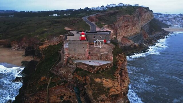 An iconic place on the Atlantic coast, the Mecca of big-wave surfing. View of Nazare's lighthouse in Zon North Canyon, place with the biggest waves in Europe, Nazare, Portugal