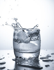 Ice cube splashes in a glass of water