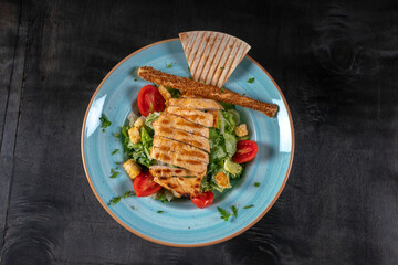 Grilled chicken steak with green olives, lettuce, cucumber, rusk, lettuce and rocket. Concept for healthy nutrition. 