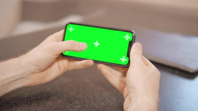 close up details male hands holding smartphone with green screen finger typing and scrolling