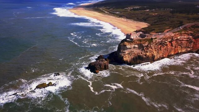 An iconic place on the Atlantic coast, the Mecca of big-wave surfing. View of Nazare's lighthouse in Zon North Canyon, place with the biggest waves in Europe, Nazare, Portugal