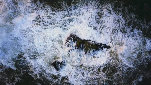 Waves crash against the rocks. An iconic place on the Atlantic coast, the Mecca of surfing on big waves.Rocks at the Nazare Lighthouse, the place with the largest waves in Europe, Nazare, Portugal