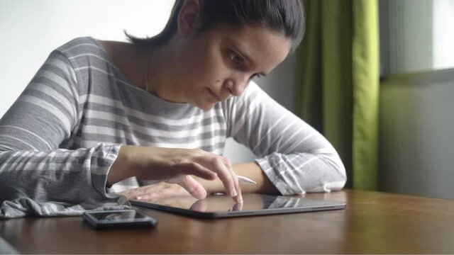 Brunette woman using tablet sitting near the window