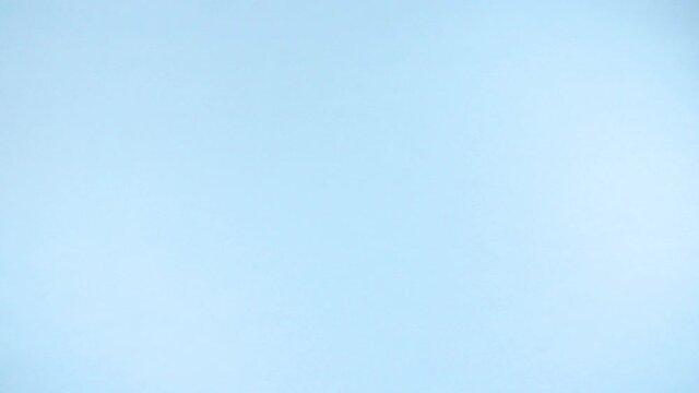 Joyful explosion of uncooked italian pasta tagliatelle flying up on a colorful light blue background in slow motion.