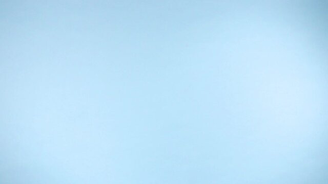 Uncooked italian mixed and multicolor pasta flying up on a colorful light blue background in slow motion.