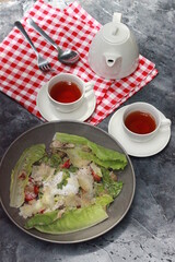 Burmese Tea Leaf Salad with vegetables, chicken and eggs with a delicious sprinkling of spices and warm tea with a red napkin mat. Healthy food menu