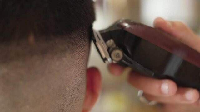 barber cutting client hair with electric razor slow motion