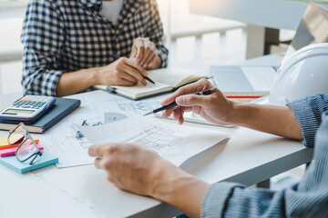 engineer Hand Drawing Plan On Blue Print with architect equipment discussing the floor plans over blueprint architectural plans at table in a modern office.
