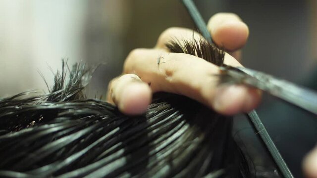 barber cutting client hair with scissors slow motion