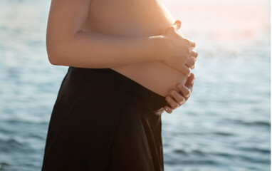 Beautiful pregnant girl at sea background in sunset